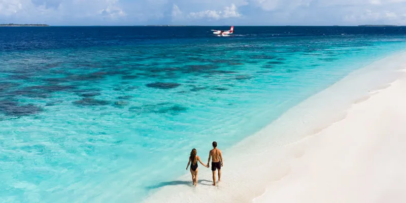 Reethi Faru Resort beach couple walk in Maldives